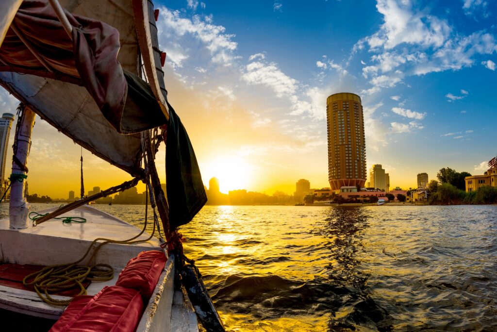 Traditional felucca sailboat gliding on the Nile River with city skyline in the background, Cairo