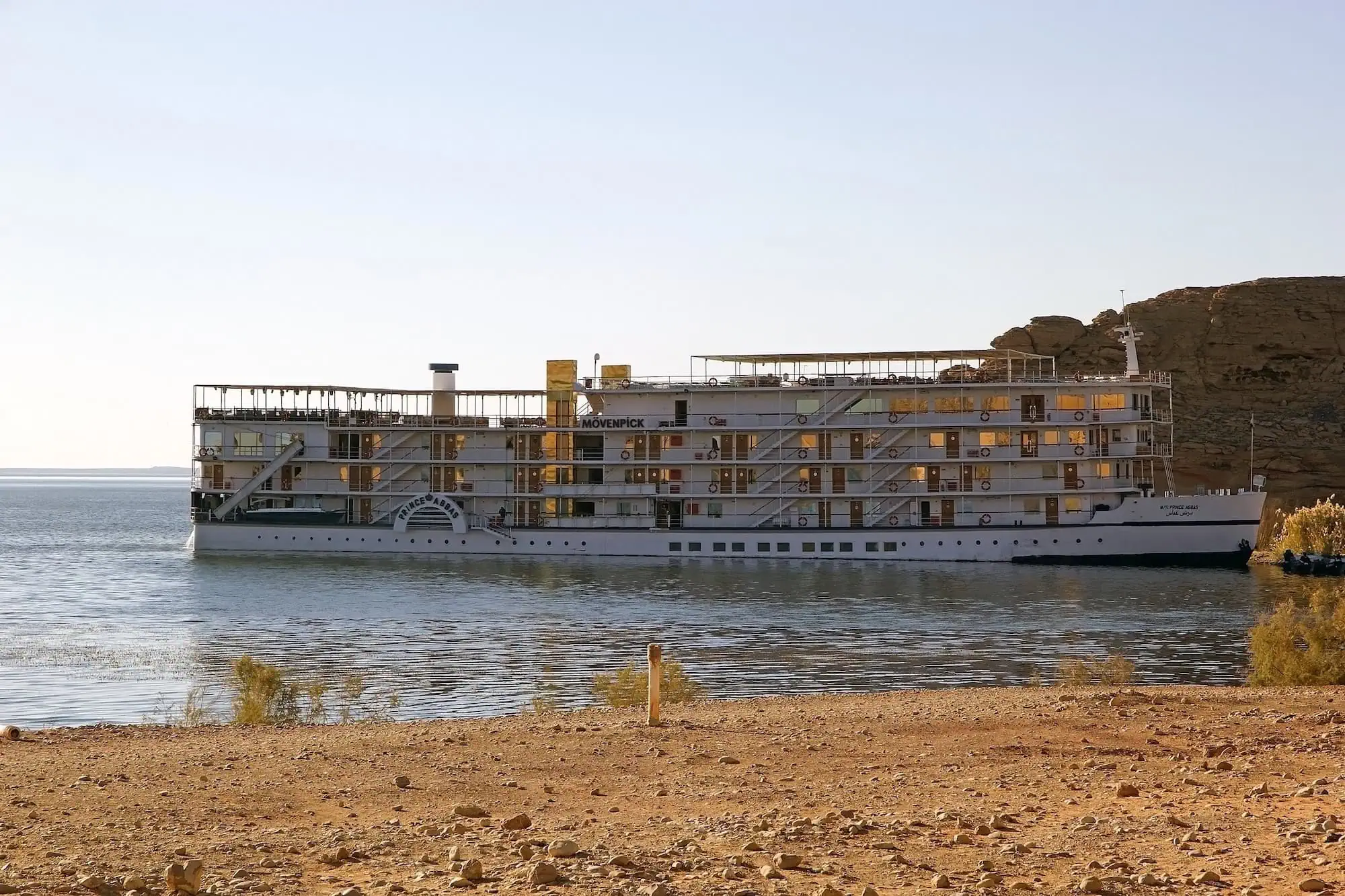White luxury cruise ship anchored on Lake Nasser with desert landscape in background