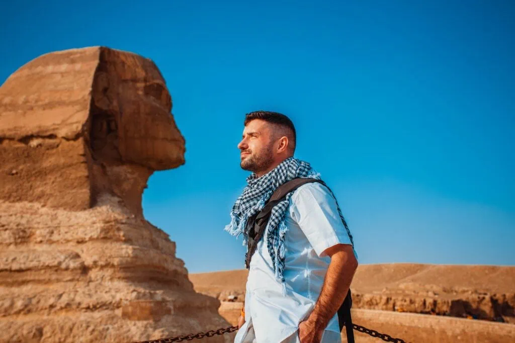 A male tourist standing in front of the Great Sphinx, Giza