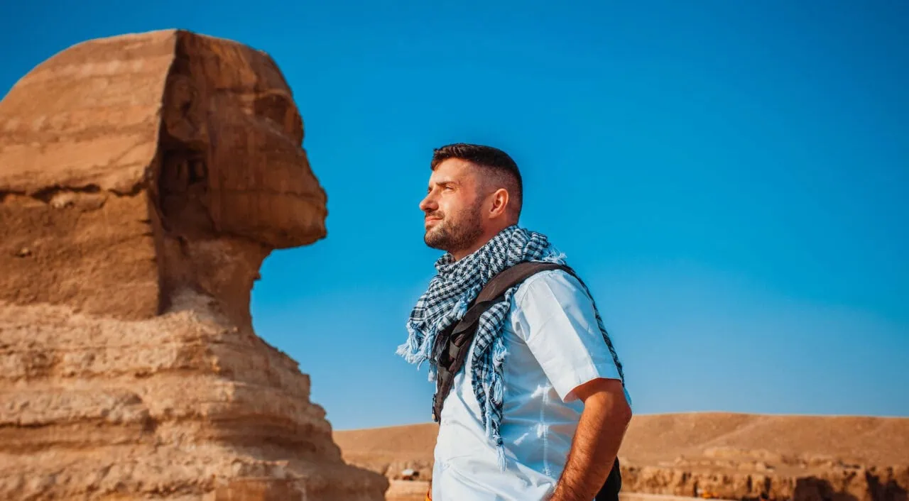 Male tourist pretends to kiss the sculpture of Giza, Egypt