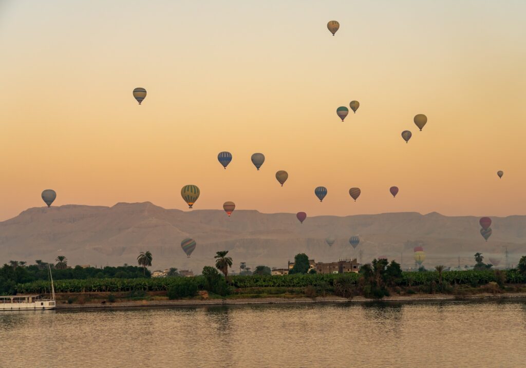 Hot air balloons floating above the Nile River at sunset during flights over the Valley of the Kings, Luxor