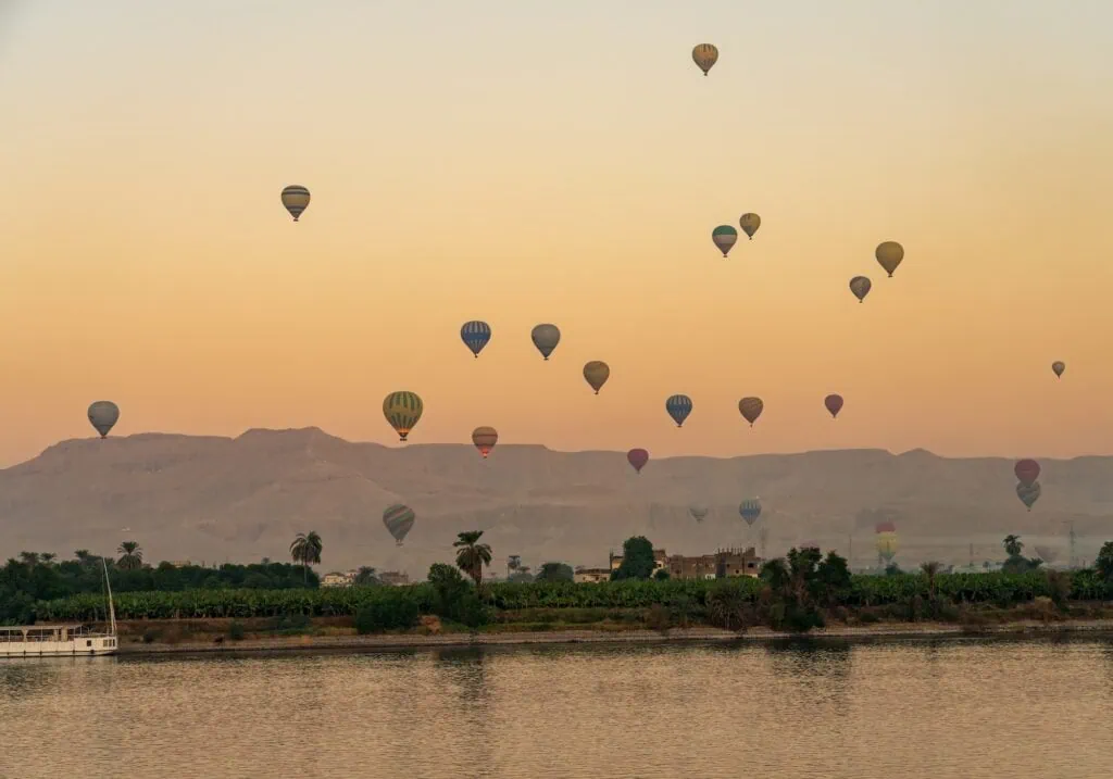 Hot air balloons floating above the Nile River at sunset during flights over the Valley of the Kings, Luxor