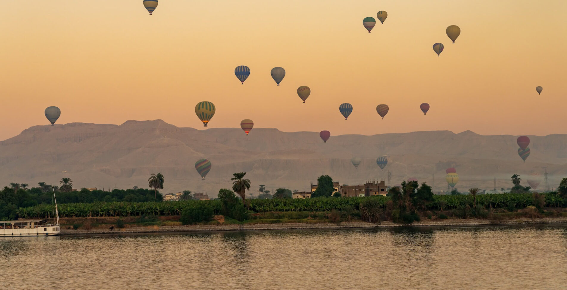 Many balloons in the sky over Nile River in Luxor for sunset flight over the Valley of the Kings 1905x976 crop y92