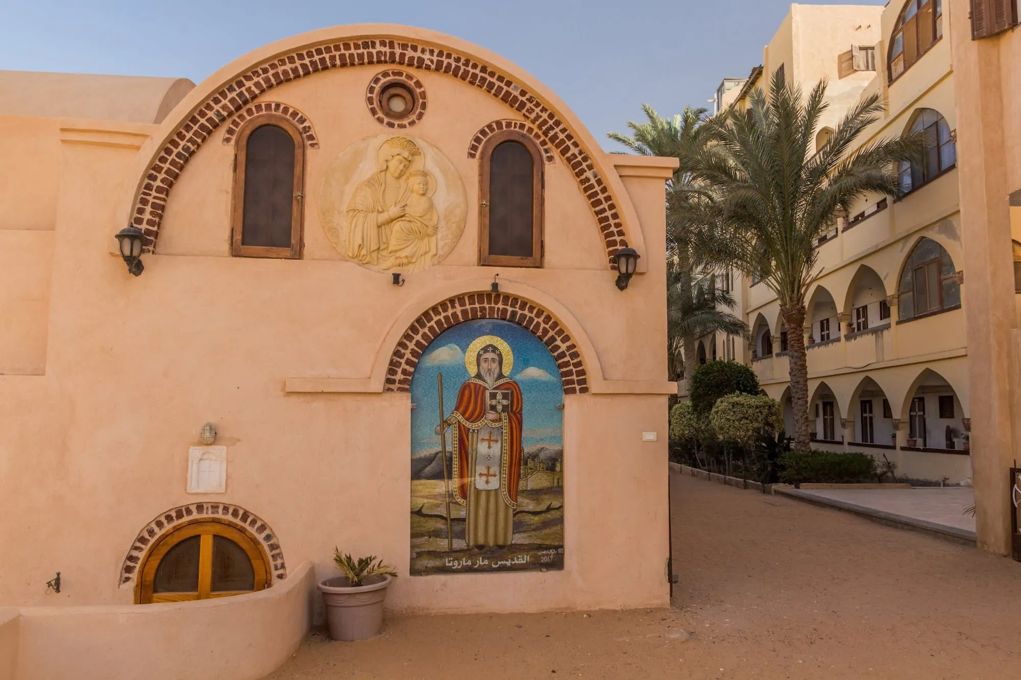 Coptic Orthodox monastery in Egypt with religious murals and palm trees
