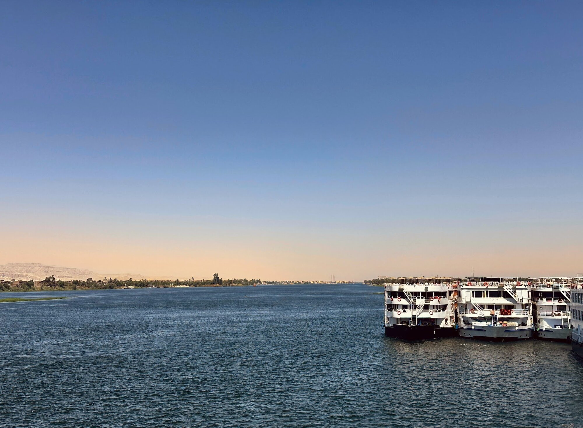 Cruise ships docked along the Nile River with desert landscape in background