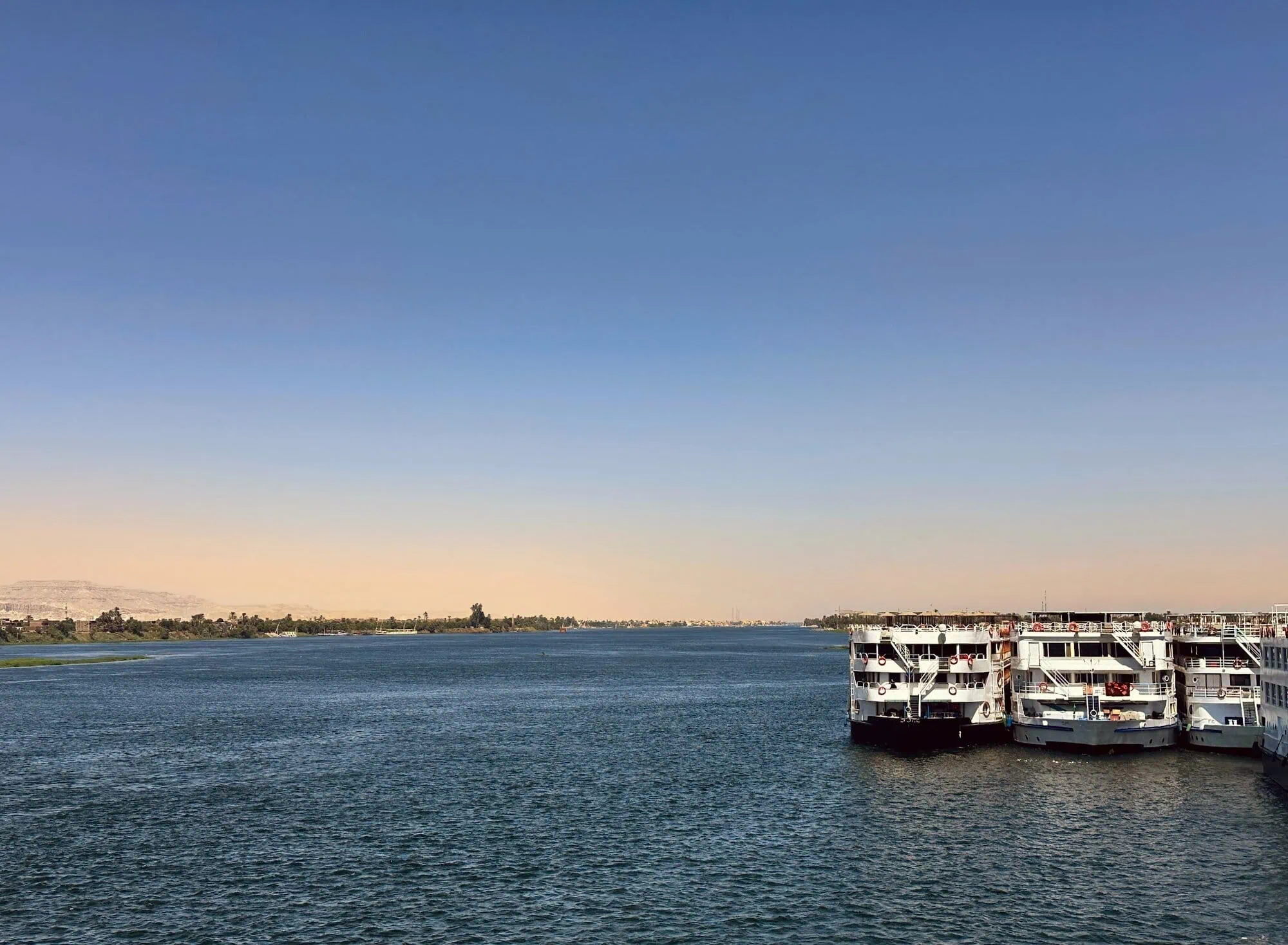 Cruise ships docked along the Nile River with desert landscape in background