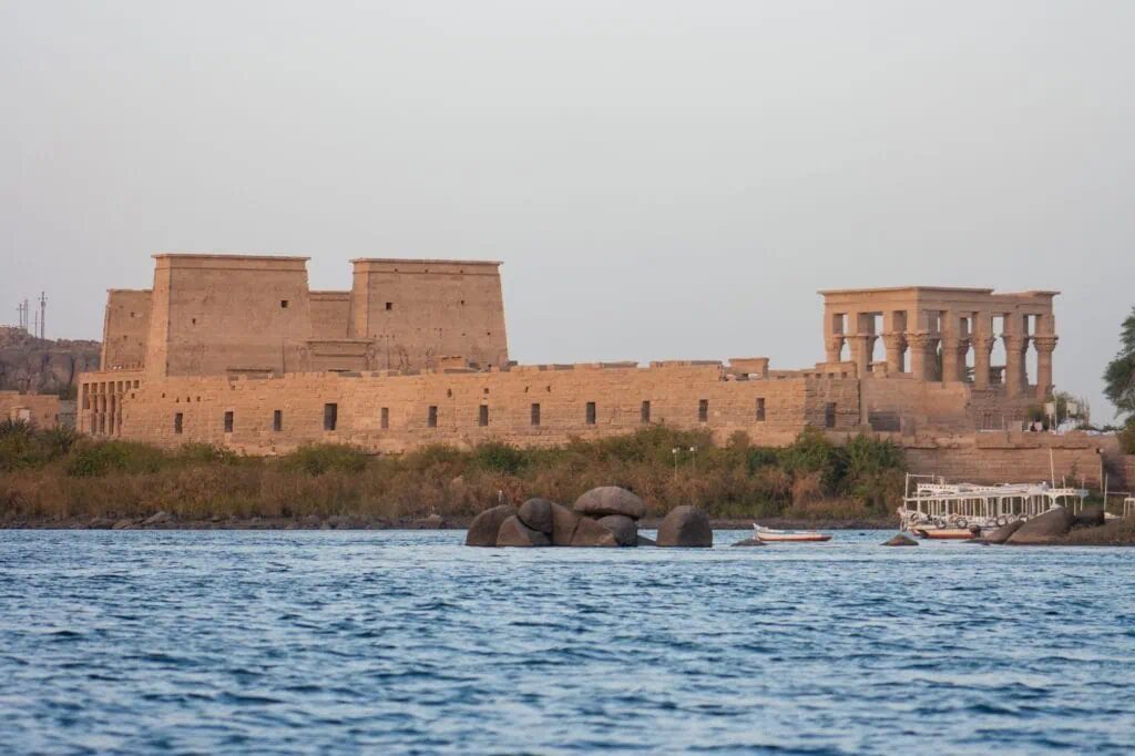 Philae Temple complex with ancient stone columns and relief carvings on the Nile River, Aswan