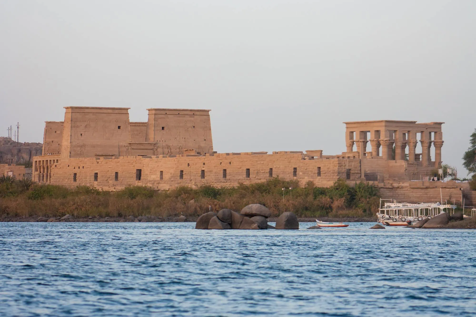Philae Temple columns rising from Lake Nasser waters with boat nearby