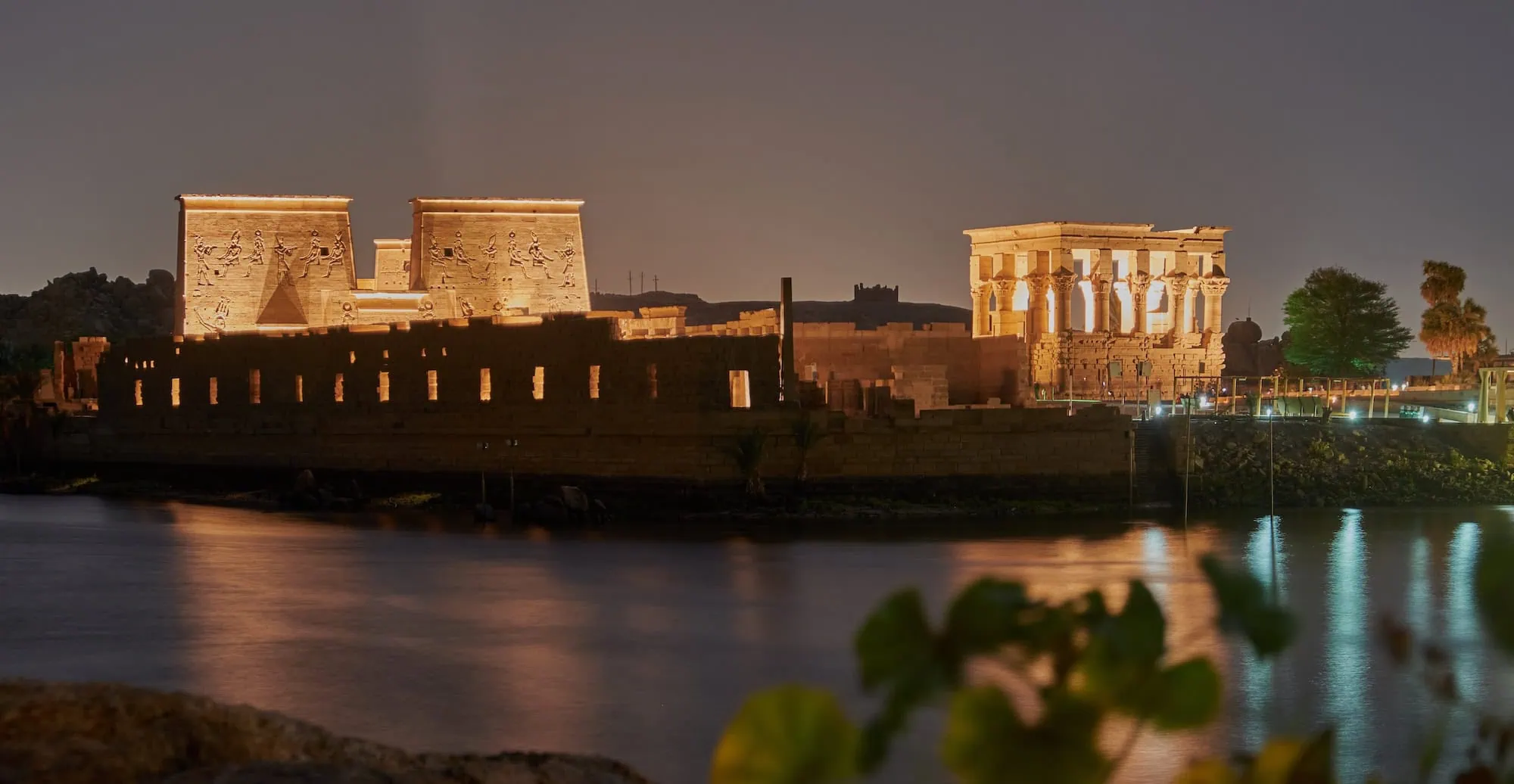 Ancient Philae Temple with hieroglyphs on illuminated columns beside the Nile River