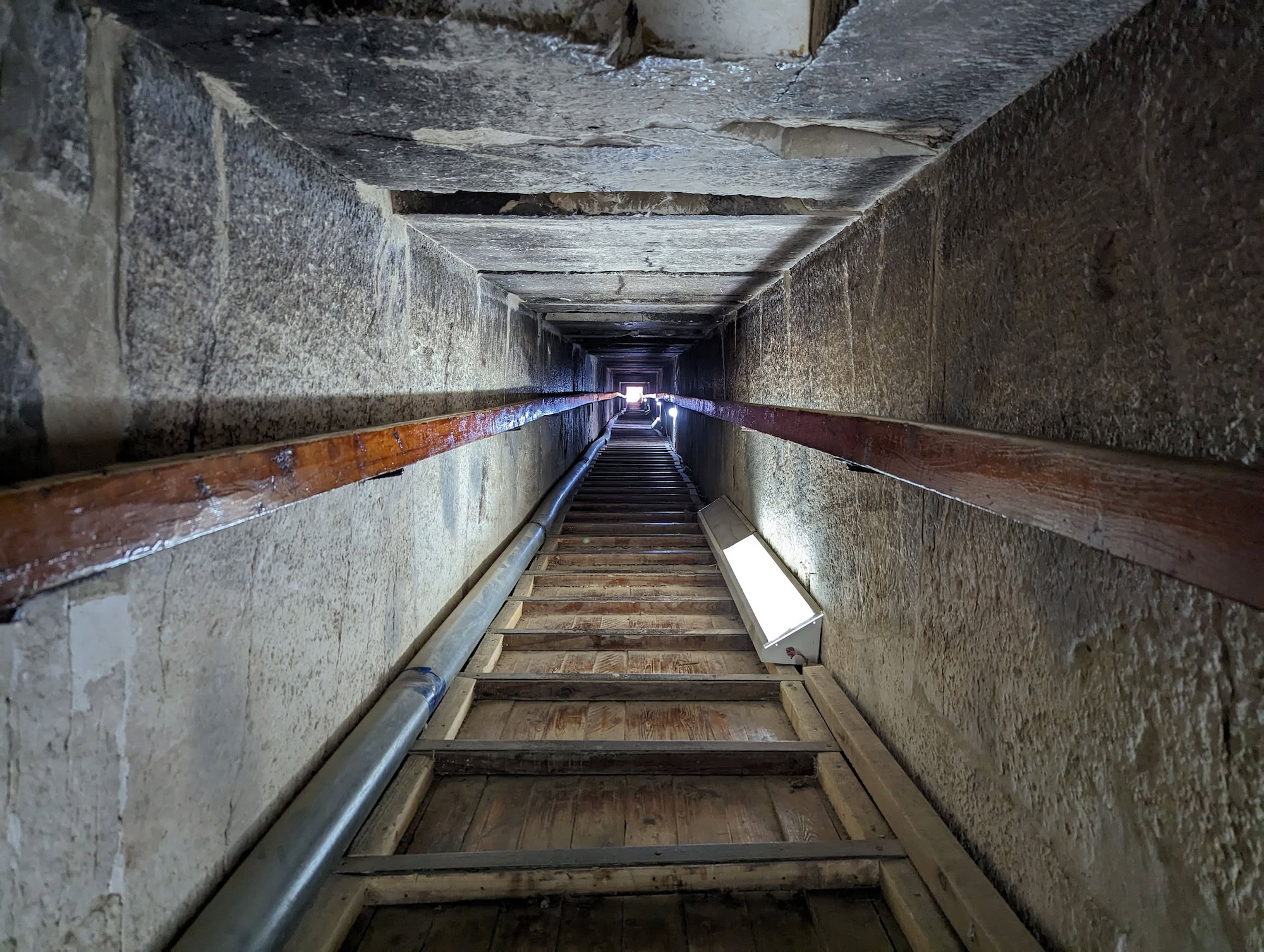 Narrow stone passage inside pyramid showing steep stairs and smooth limestone walls