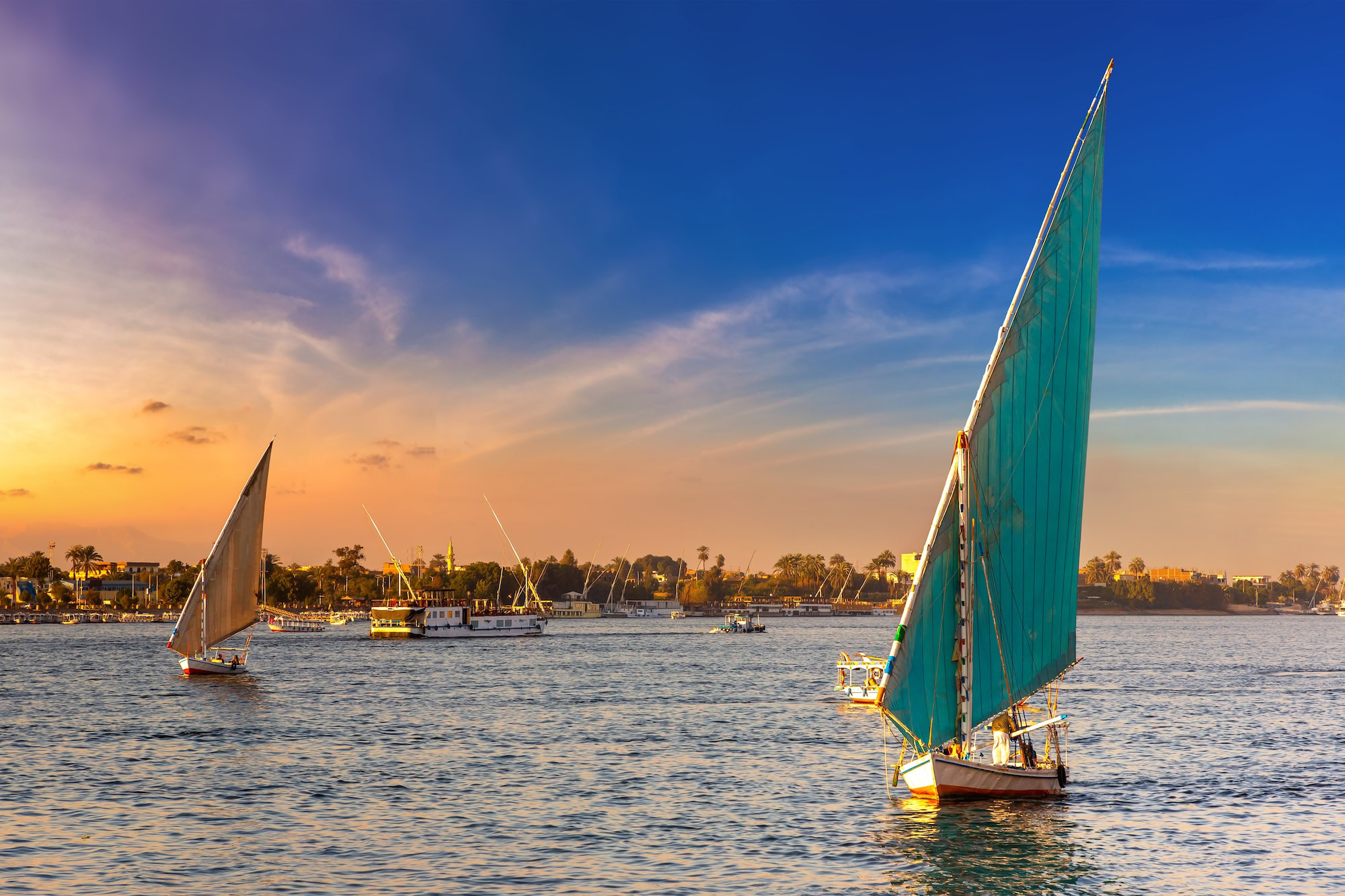 Traditional felucca sailboats on the Nile River at sunset in Aswan