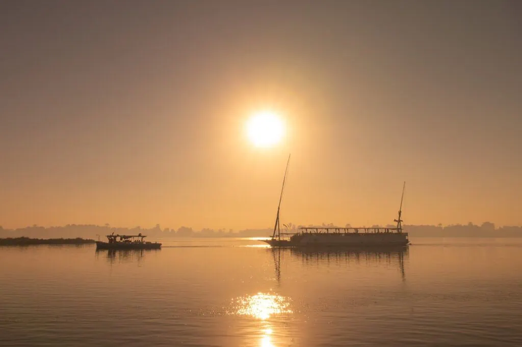 Silhouette of a traditional egyptian dahabiya boat cruising on the Nile river at sunset Egypt