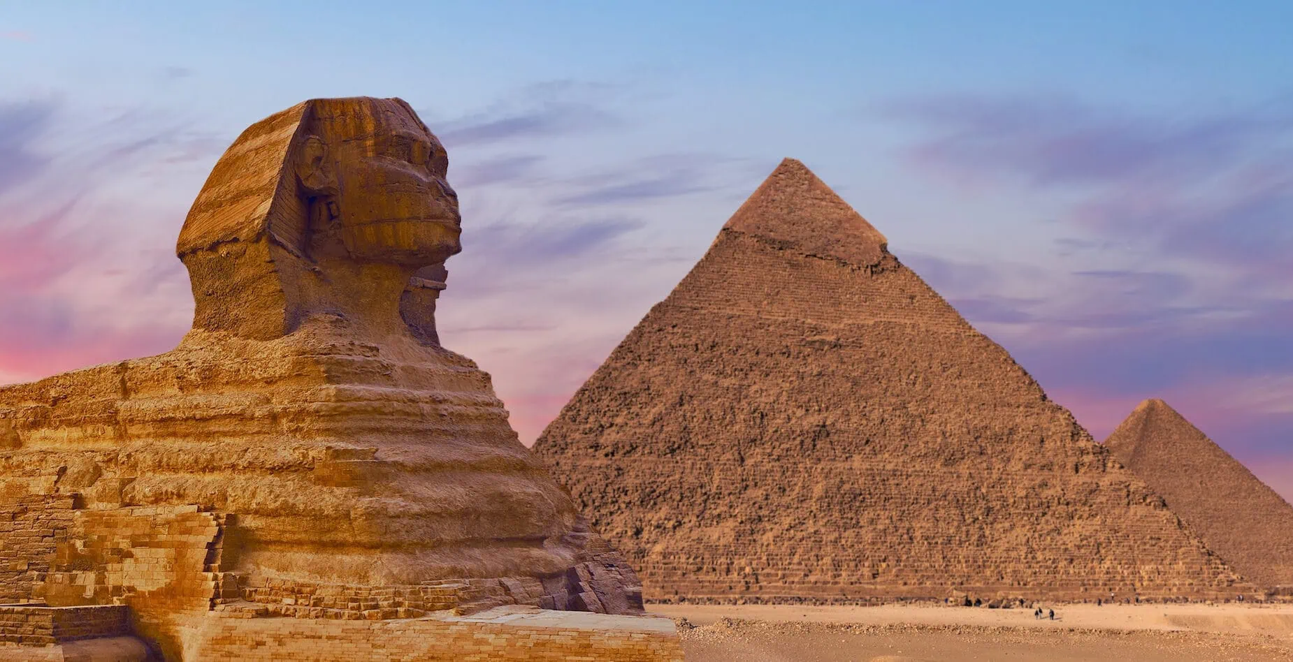 Sphinx against the backdrop of the great Egyptian pyramids. Africa Giza Plateau 1850x948 crop 49 75