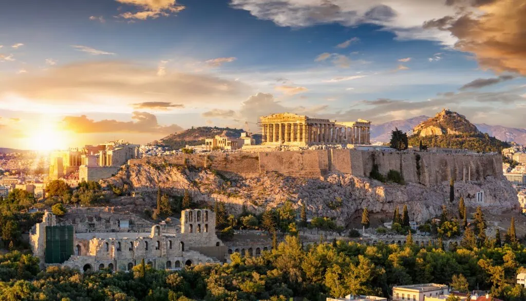 The Acropolis of Athens at sunset, with the marble columns of the Parthenon temple standing on top of the hill above the city, Greece.
