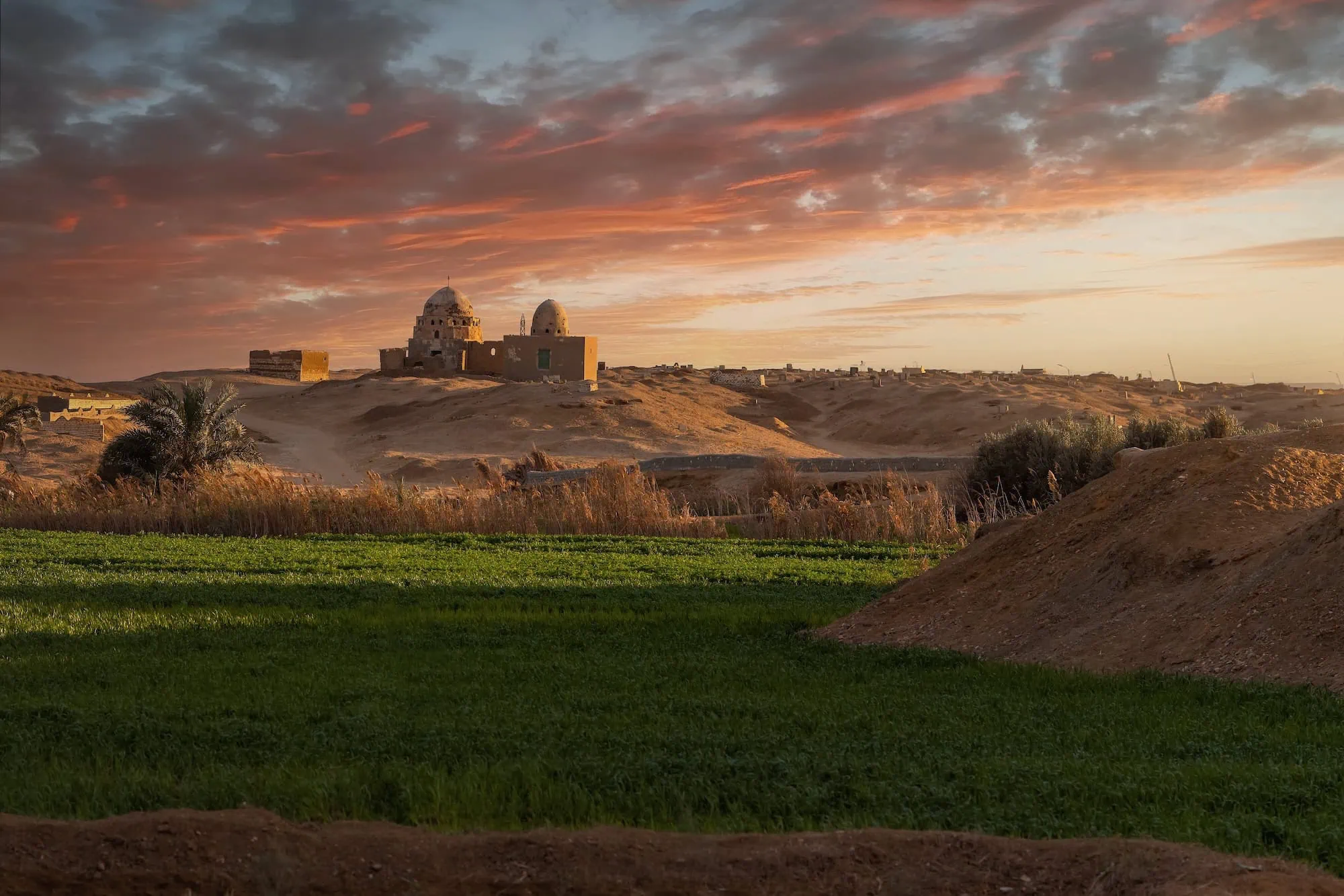 Ancient tomb complex at Beni Hassan with dome structures and green landscape