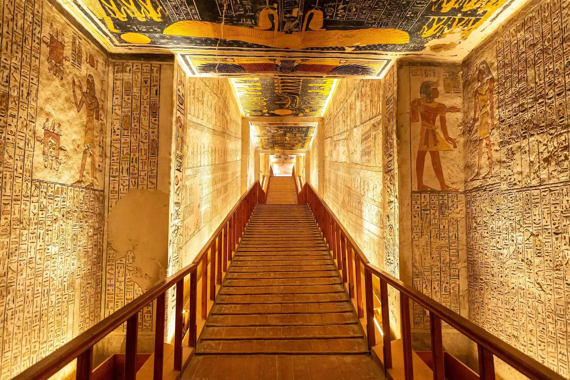 Steep stone staircase descending into Valley of the Kings tomb with low ceiling and handrails