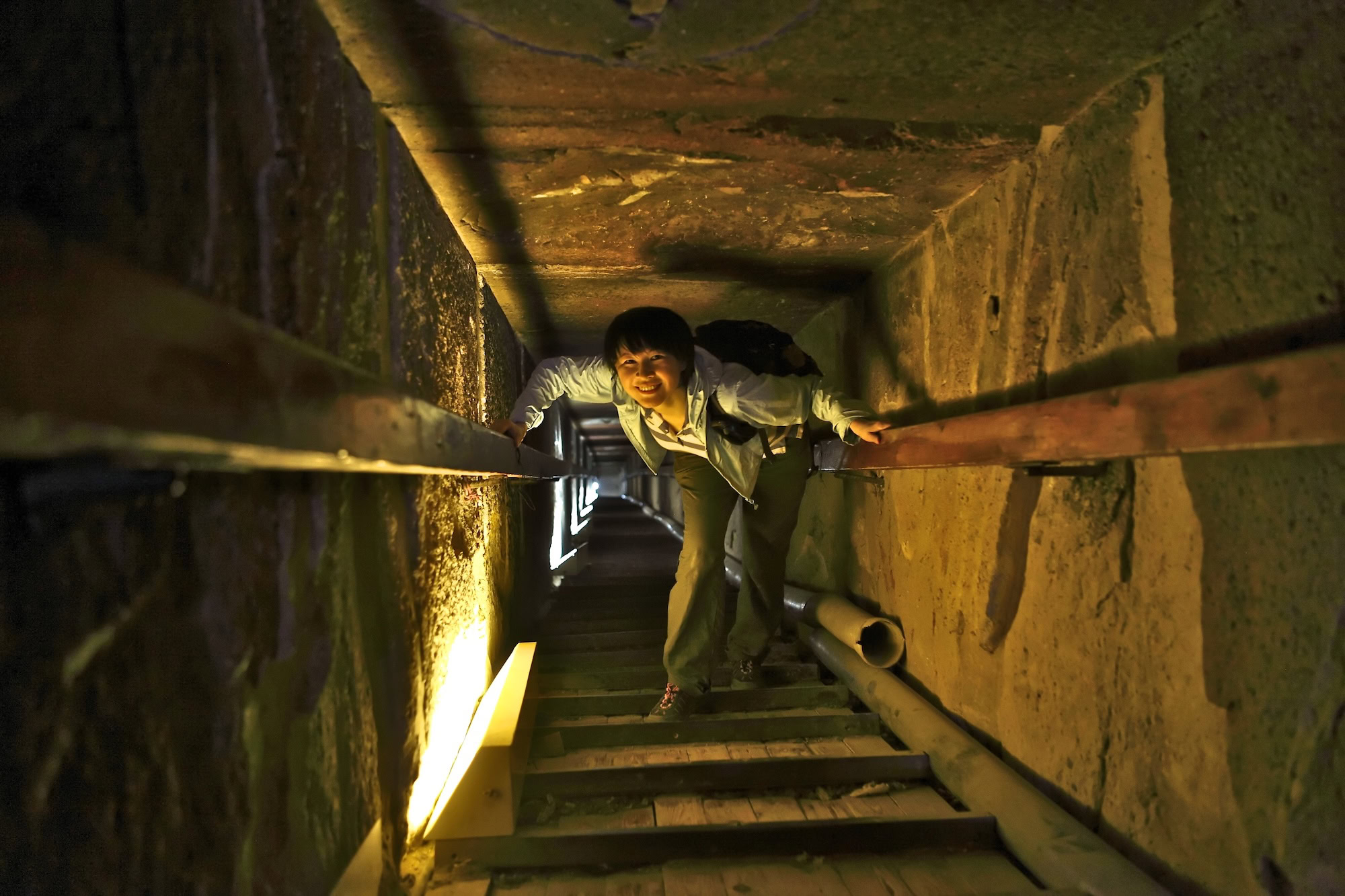Tourist exploring narrow stone passage inside Great Pyramid with ancient limestone walls