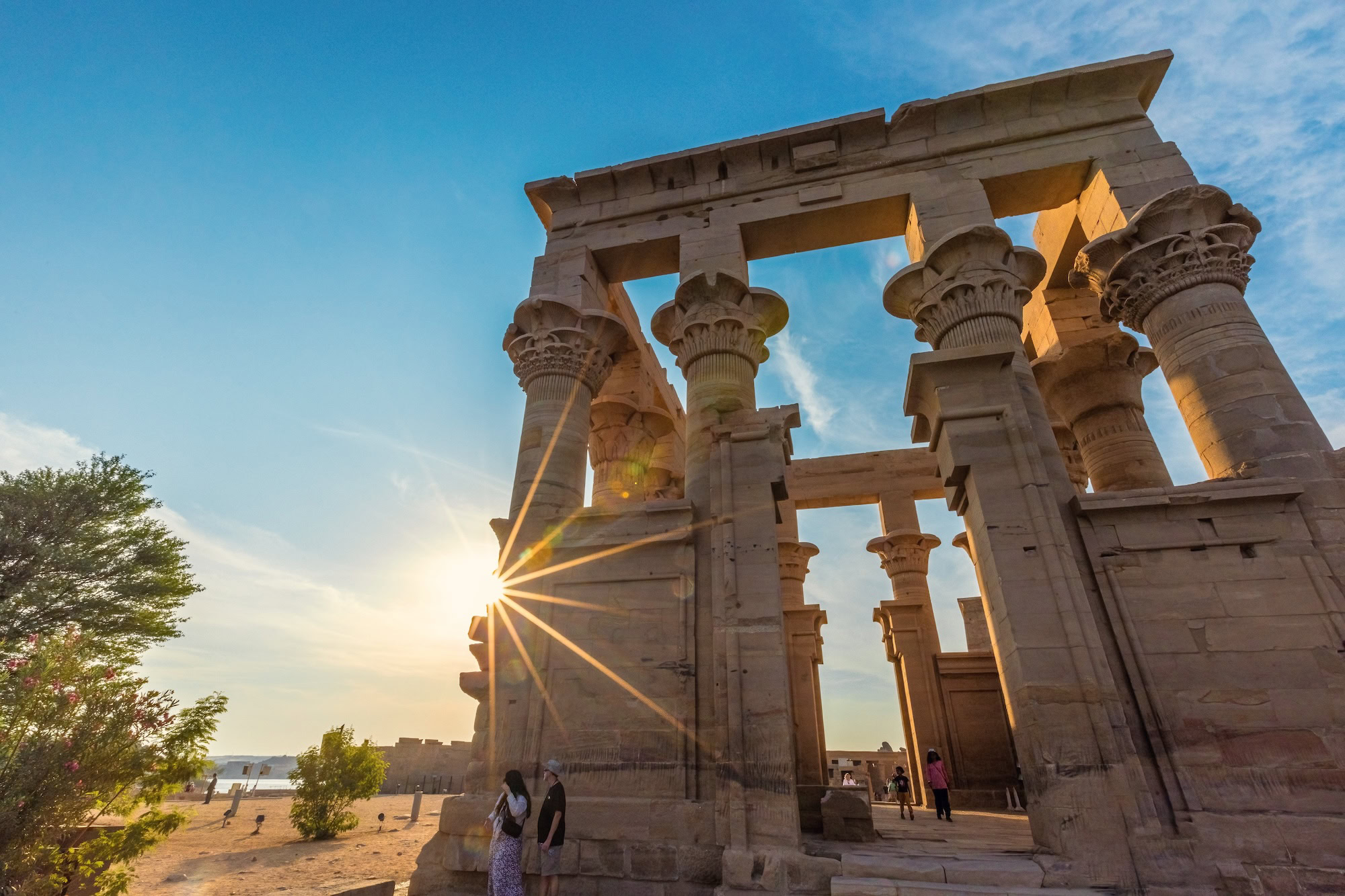 Ancient Philae Temple columns with carved capitals and tourists exploring the magnificent Egyptian monument