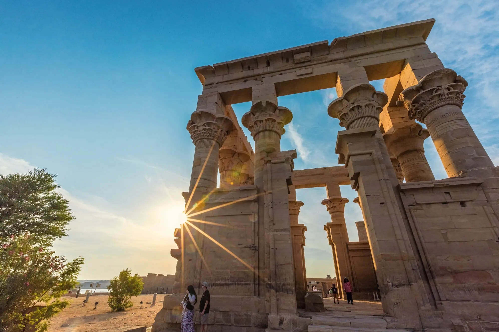 Ancient Philae Temple columns illuminated by golden sunlight with carved capitals and hieroglyphic details
