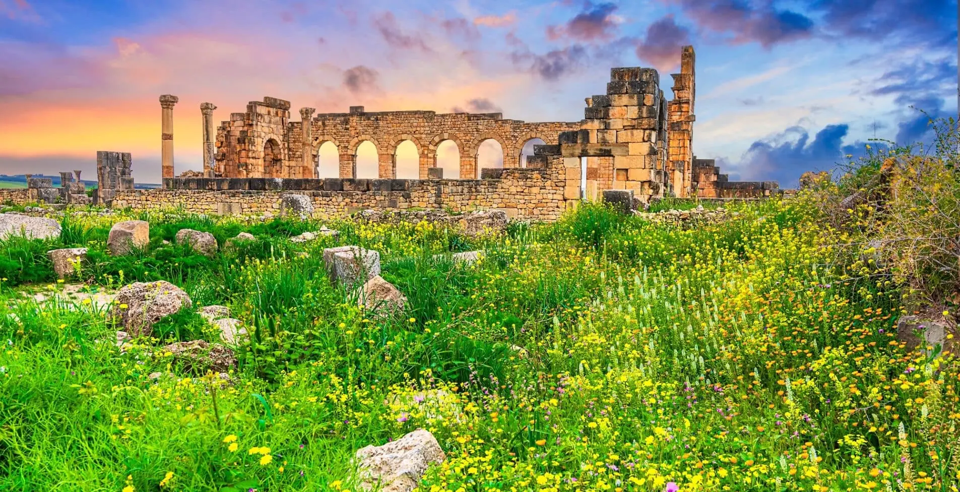 Volubilis Morocco The outer wall of the basilica with Corinthian columns at sunset. Historical city of Roman Mauretania 1905x976 crop 48 30