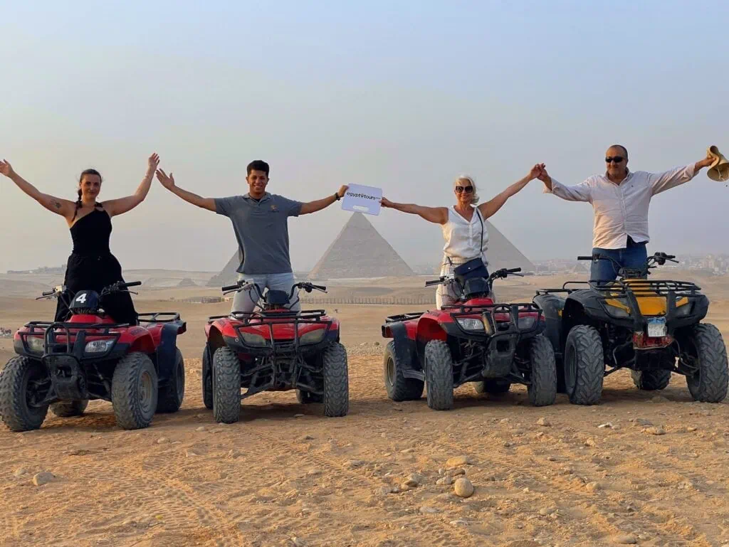 Group of tourists riding quad bikes near the Pyramids of Giza on the desert plateau, Giza