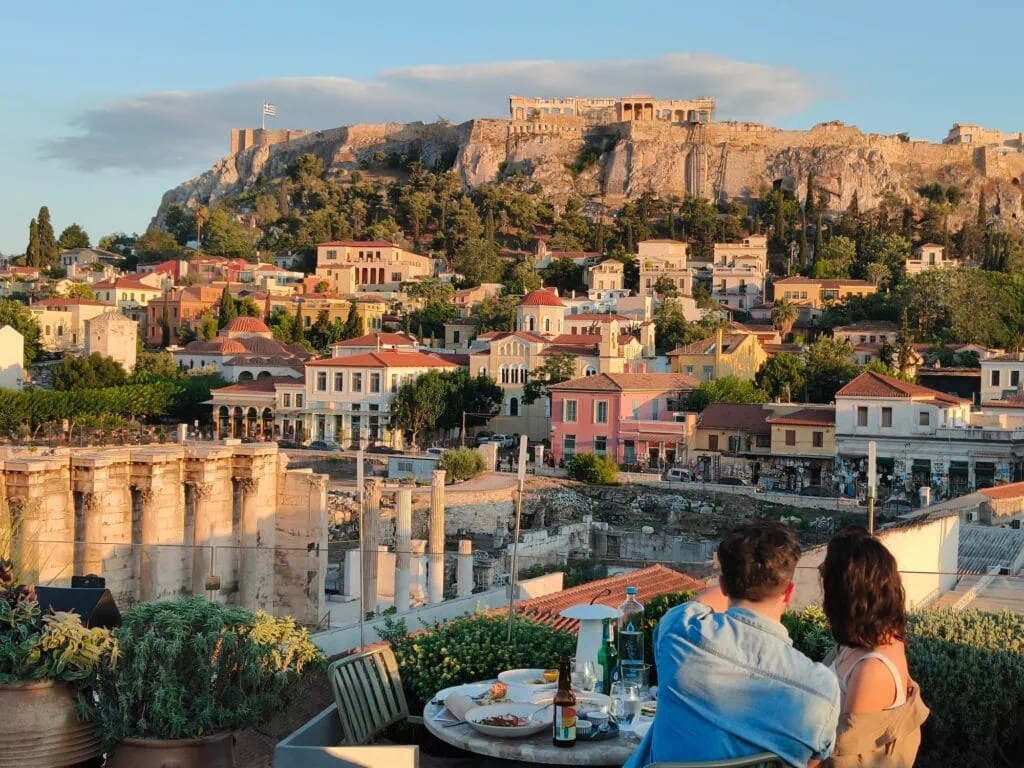 Couple dining at a rooftop restaurant with views of the Acropolis and the Ancient Agora, Athens