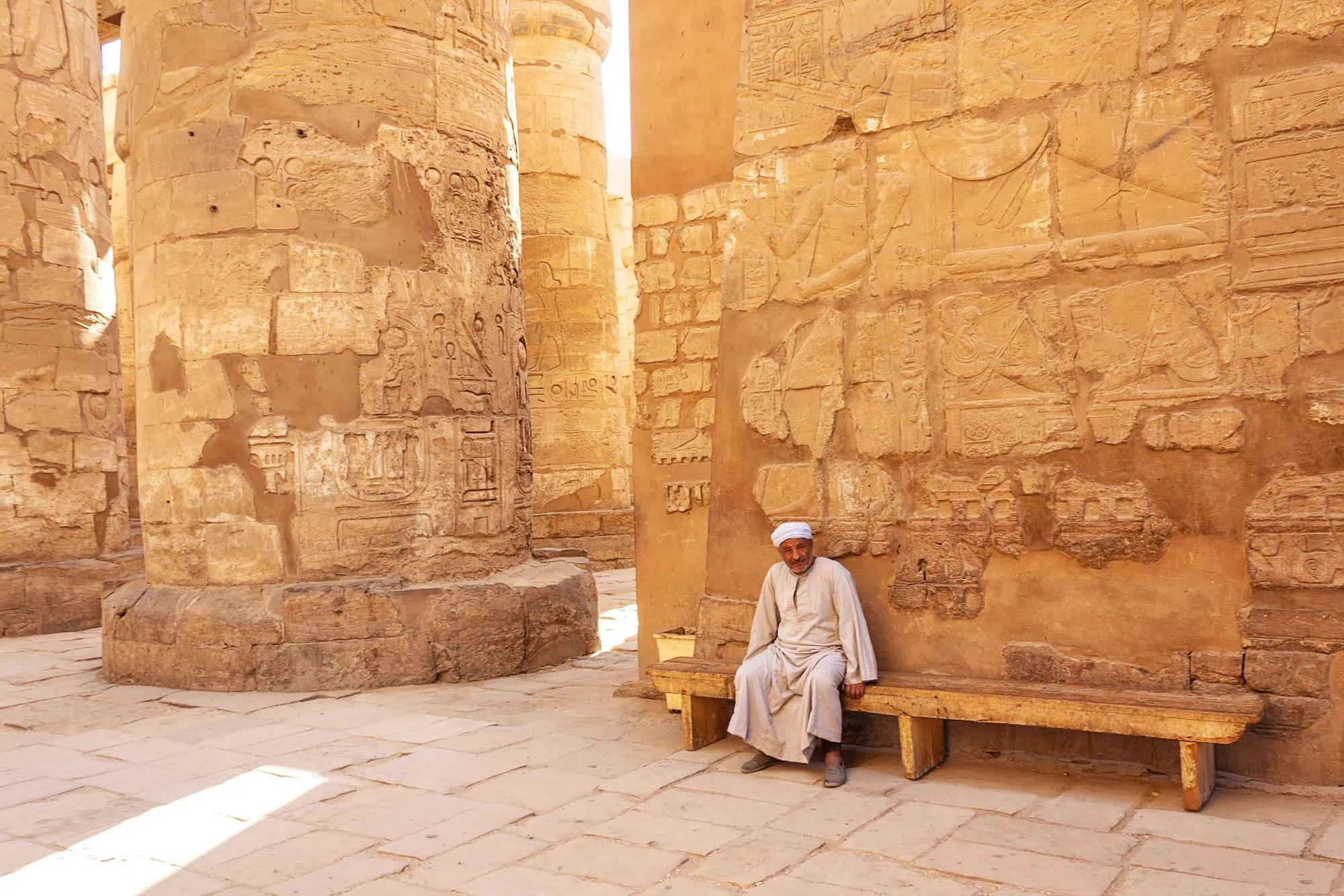 Ancient stone columns at Karnak Temple with a temple guard in traditional clothing, Luxor