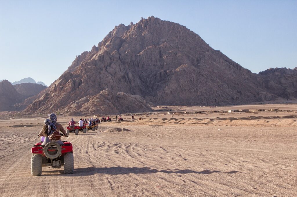 Off-road quad bikes crossing a desert plain with mountain backdrop, South Sinai Desert, Sharm El Sheikh