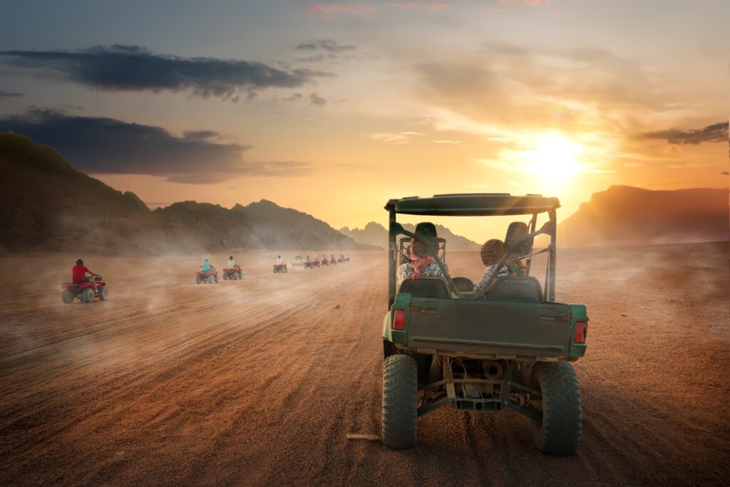 Off-road buggy driving across desert sand dunes at sunset, Hurghada