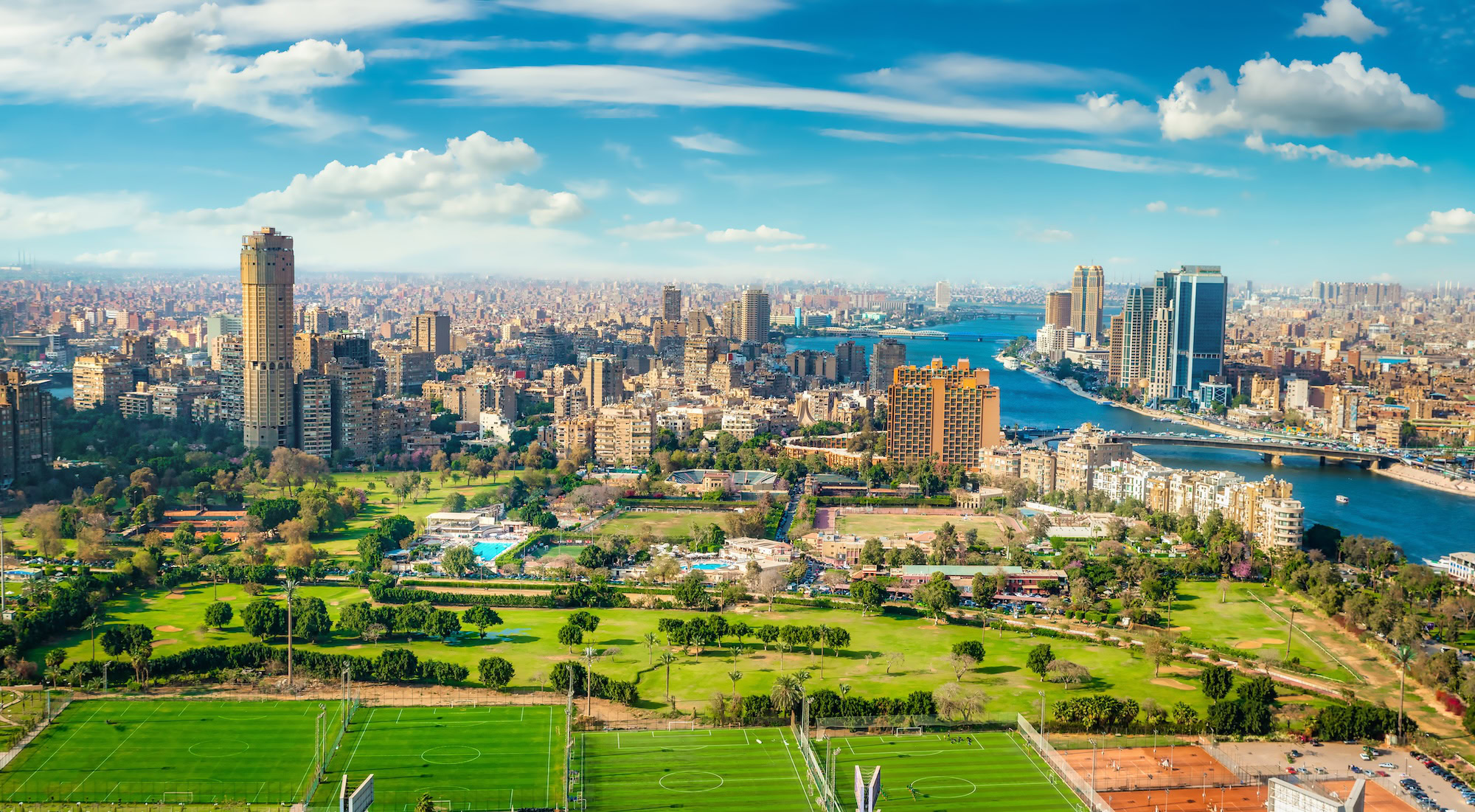 Aerial view of Cairo skyline along the Nile River with buildings and green spaces