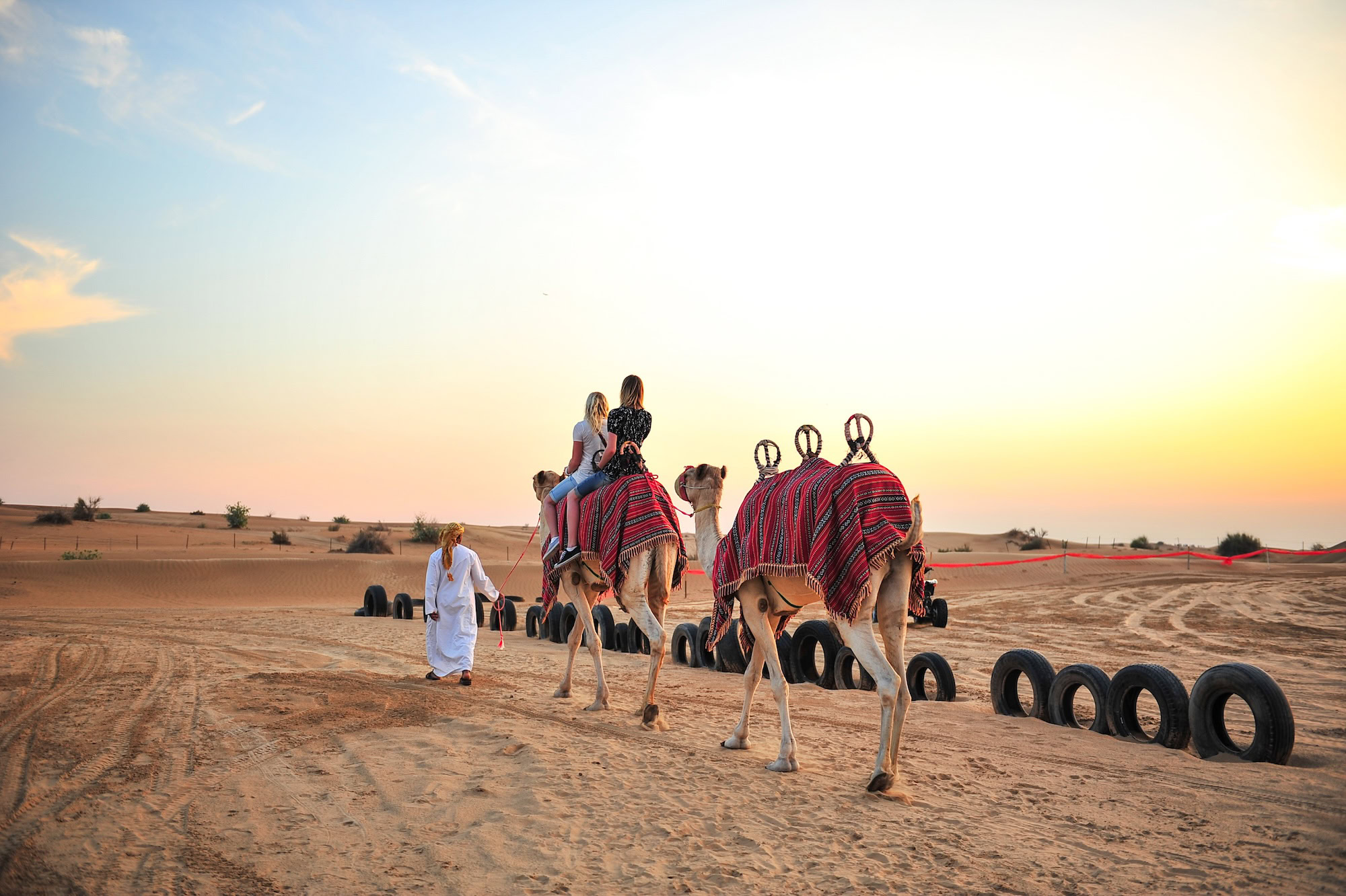 Camels and people in Dubai desert with traditional blankets during safari experience