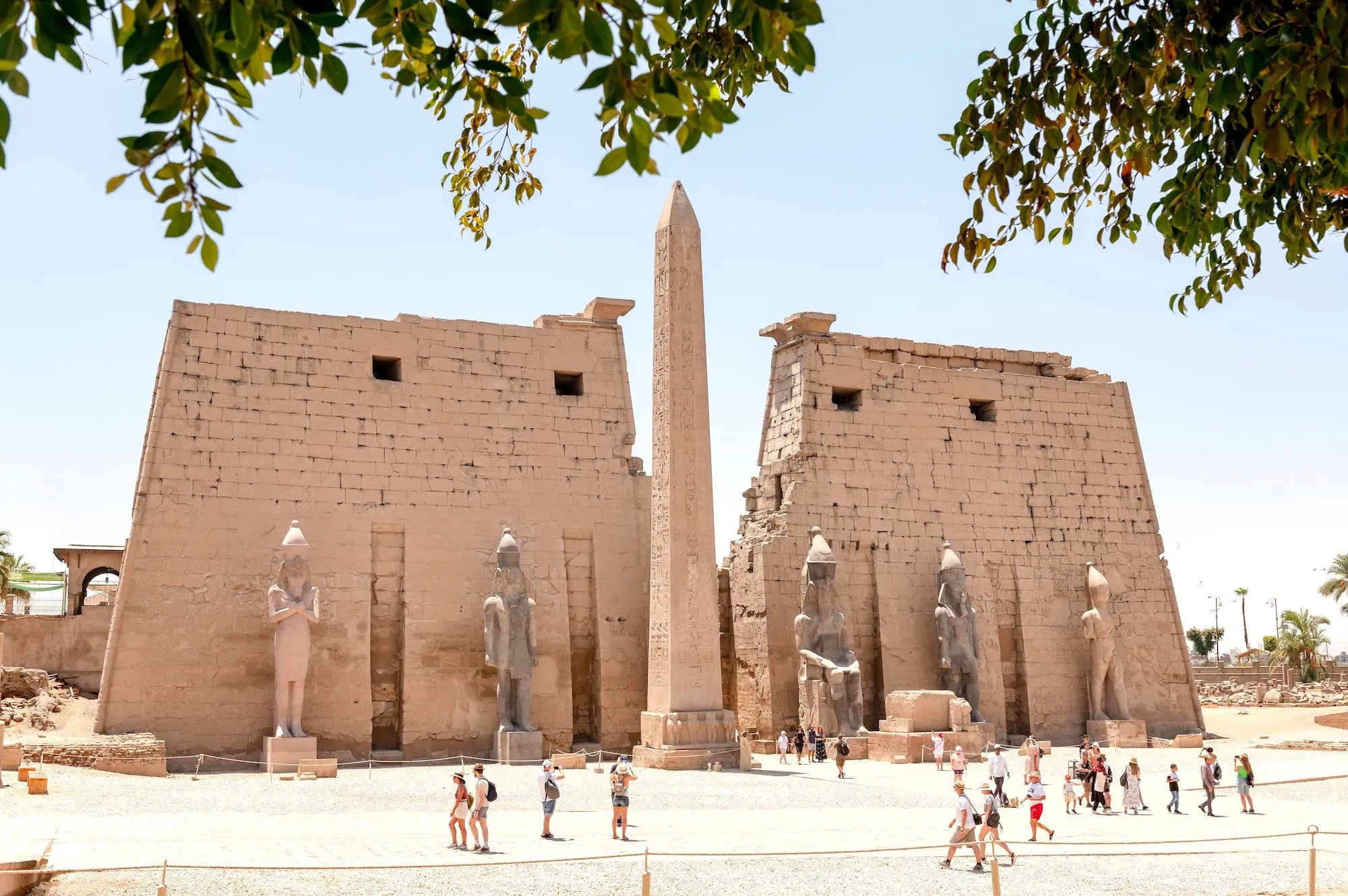 Tourists visiting Luxor Temple with ancient obelisk and stone architecture