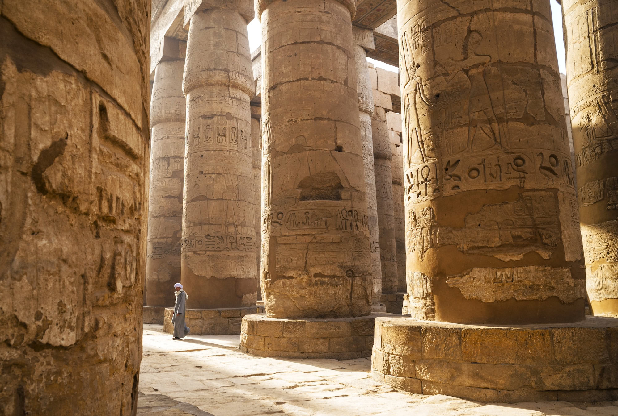 Visitors exploring the massive stone columns of the Great Hypostyle Hall at Karnak Temple
