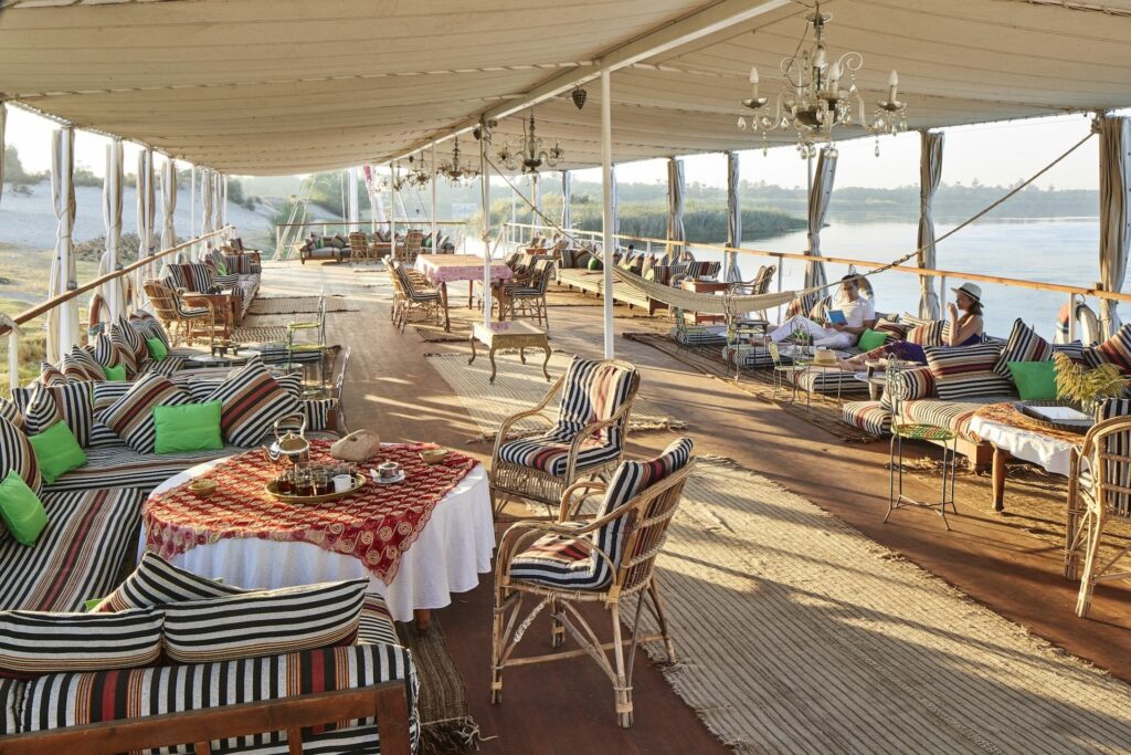 Guest relaxing on the sun deck of Nour El Nil Dahabiya overlooking the Nile
