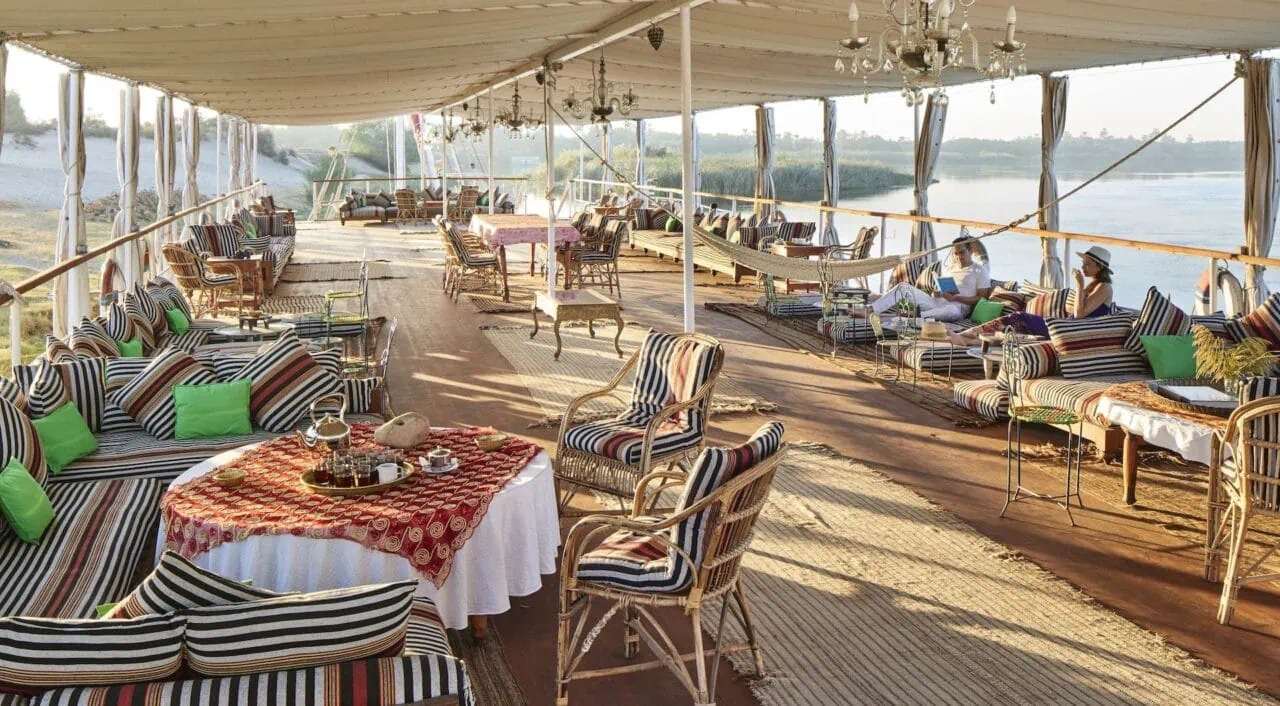 Guest relaxing on the sun deck of Nour El Nil Dahabiya overlooking the Nile