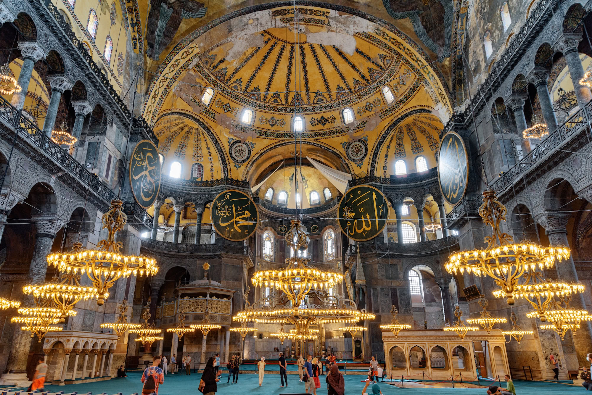Interior view of Hagia Sophia showing magnificent dome, chandeliers, columns and Islamic calligraphy medallions