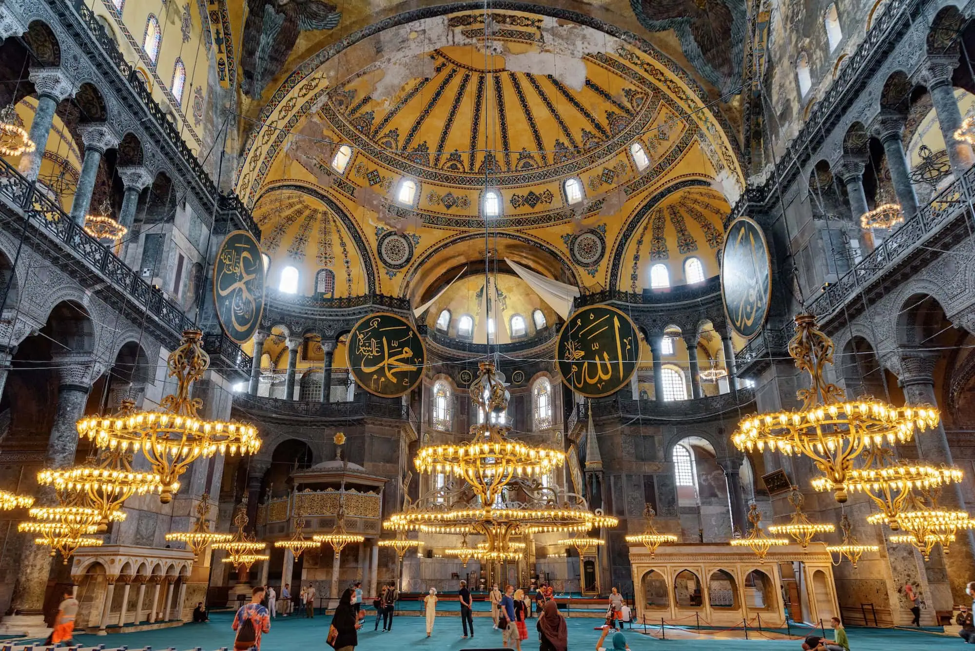 Interior view of Hagia Sophia showing magnificent dome, chandeliers, columns and Islamic calligraphy medallions