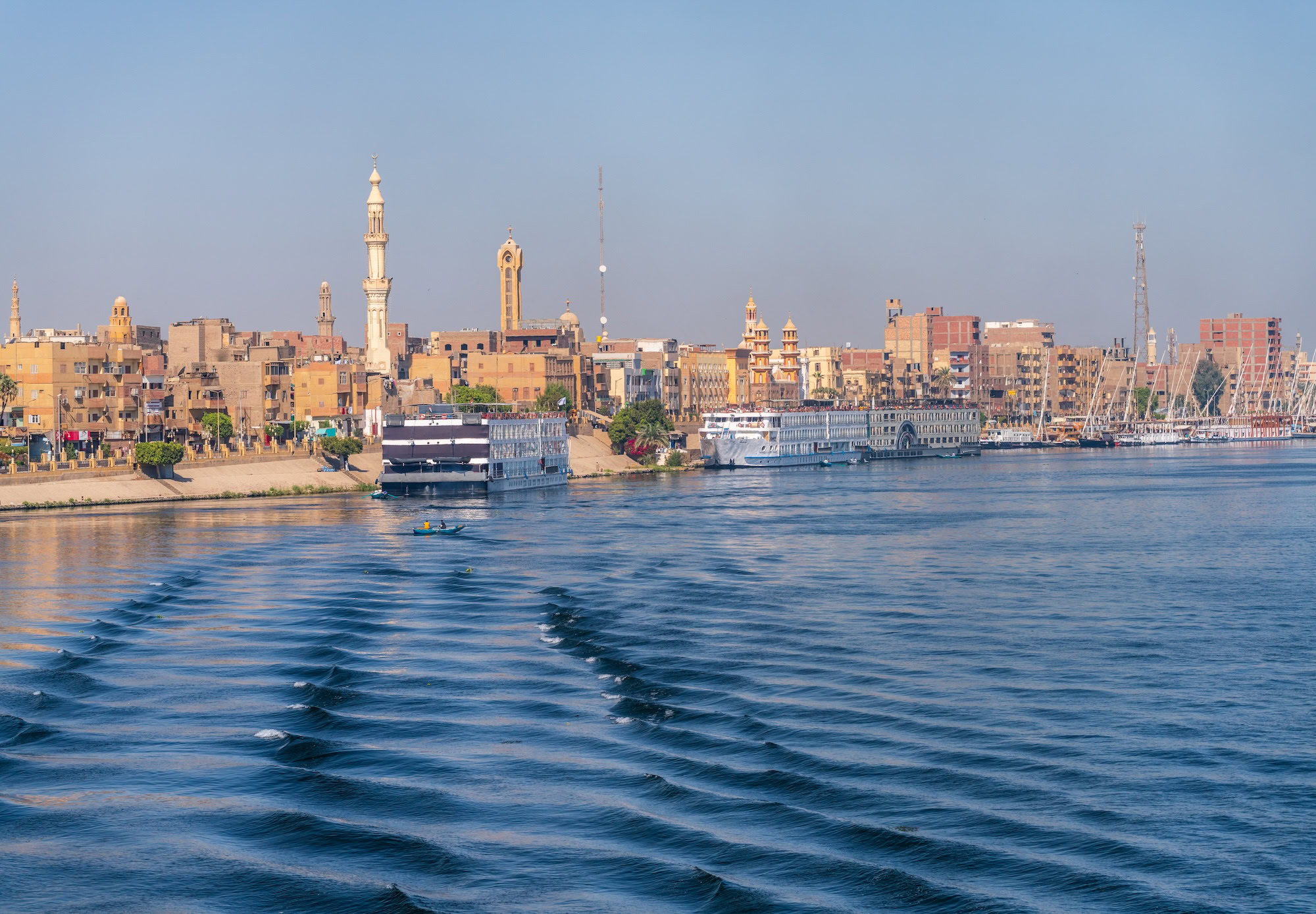 Nile River waterfront in Egypt with boats, buildings and mosque minarets along the shore