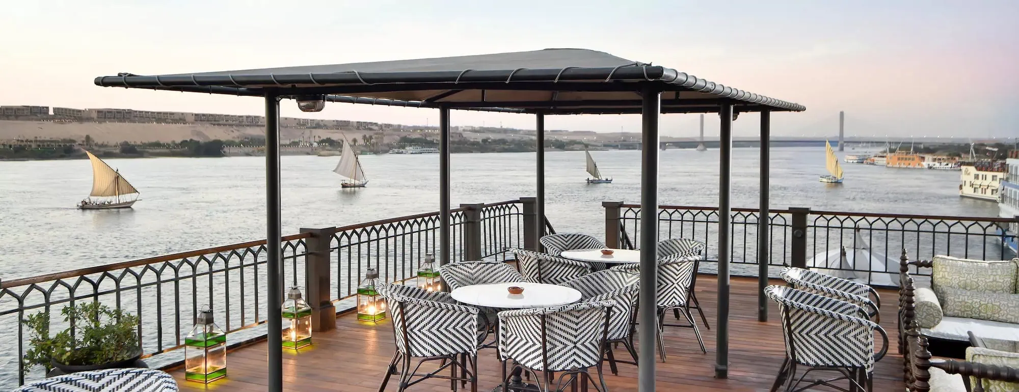 Luxury dining terrace overlooking the Nile River with elegant table setting and cruise boats