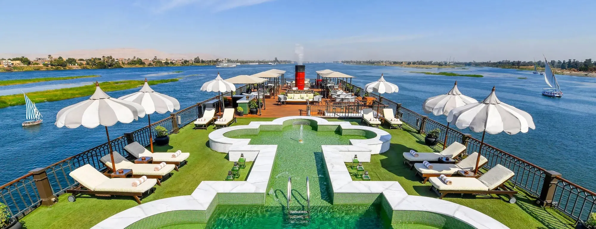 Swimming pool with sun loungers and umbrellas on cruise ship deck