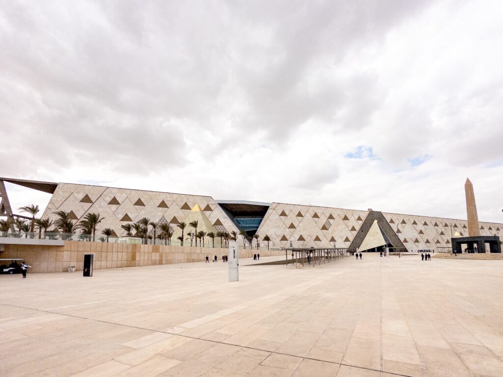 Exterior view of the Grand Egyptian Museum with modern architectural façade and surrounding open plaza, Giza