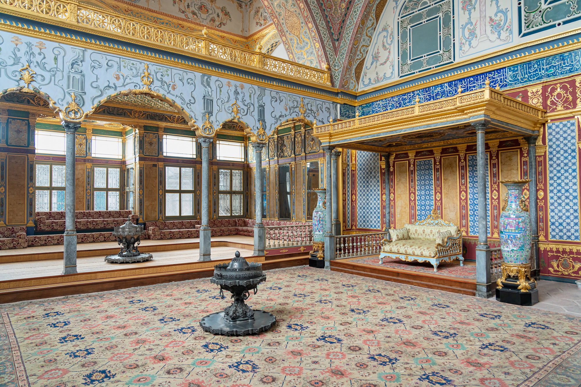 Ornate golden throne with decorative columns and Persian carpet in Topkapi Palace