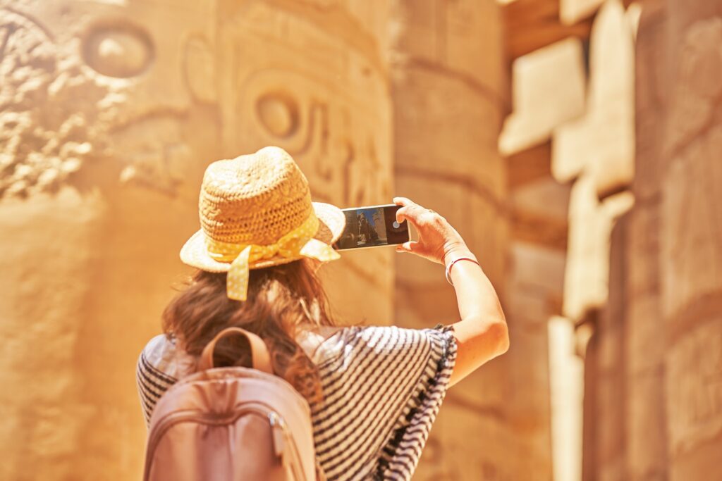 Woman visiting towering Karnak Temple columns in Luxor