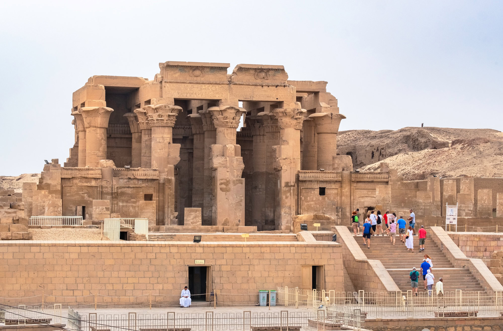 Small group of tourists exploring ancient columns and hieroglyphs at Kom Ombo Temple
