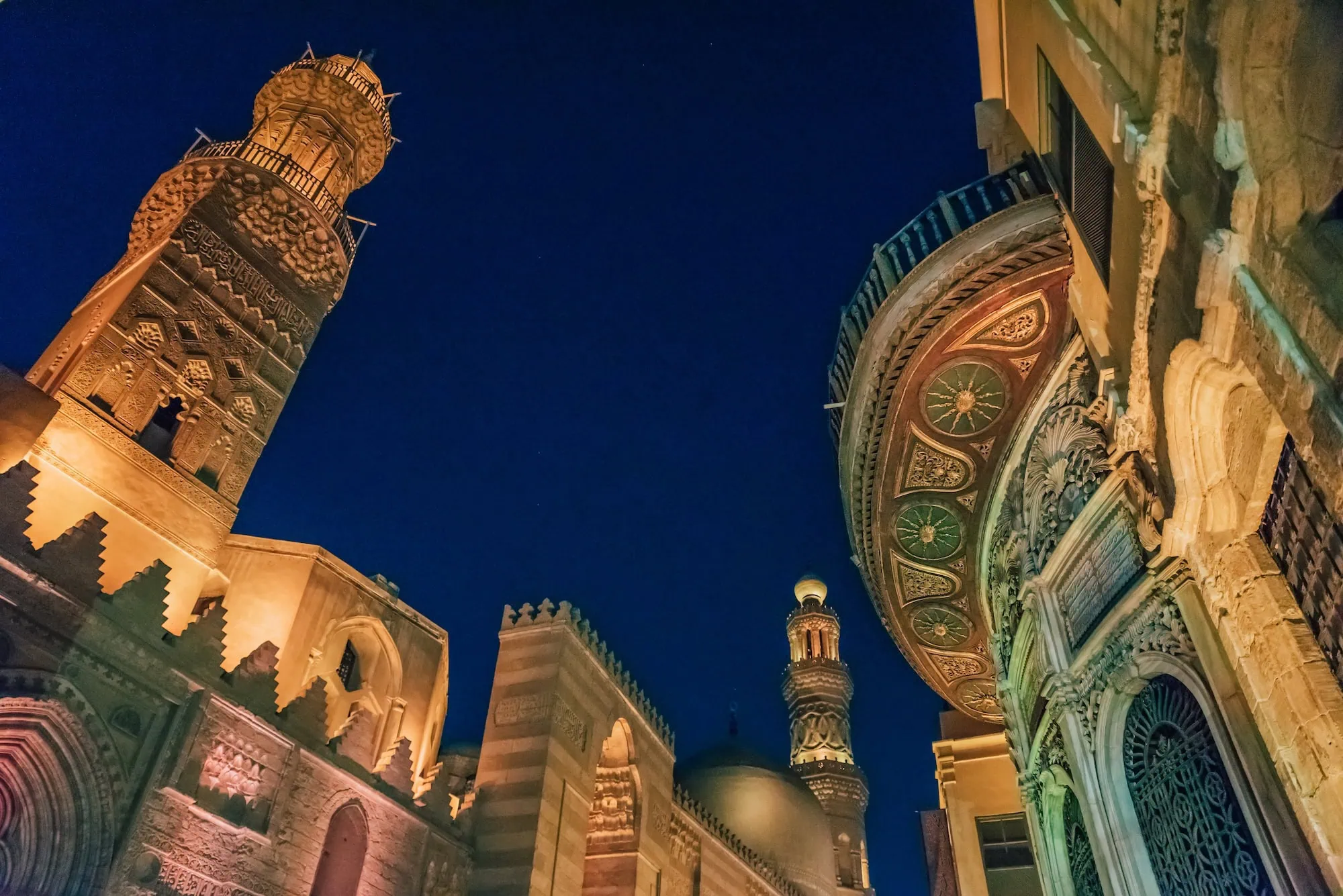 Illuminated Islamic Cairo mosque complex with minarets and domes at night