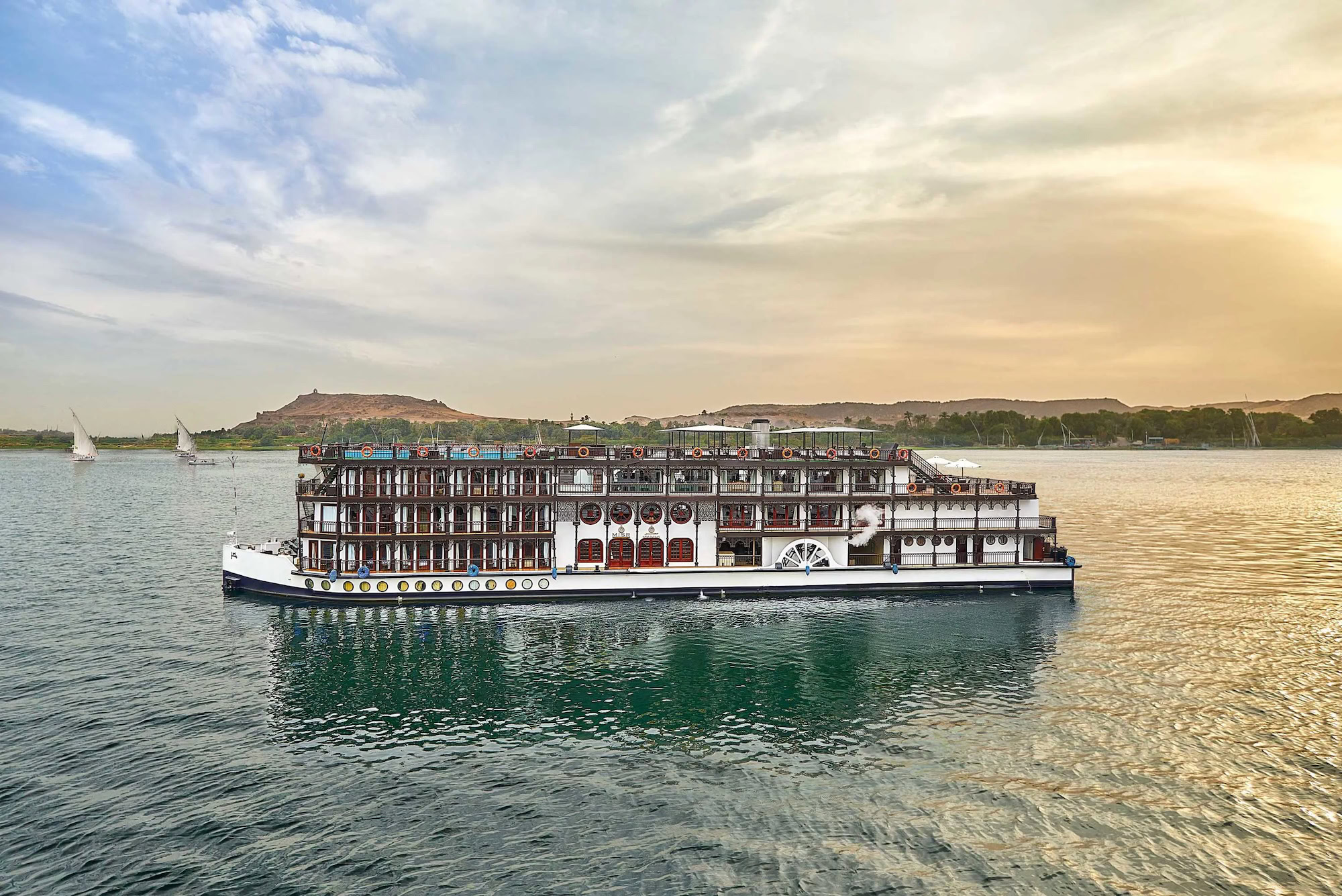 Nile River cruise ship with traditional paddlewheel sailing along the desert landscape