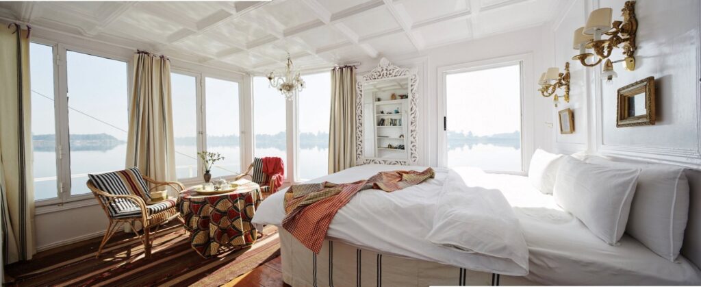 Panoramic suite with large windows and seating area aboard Nour El Nil Dahabiya