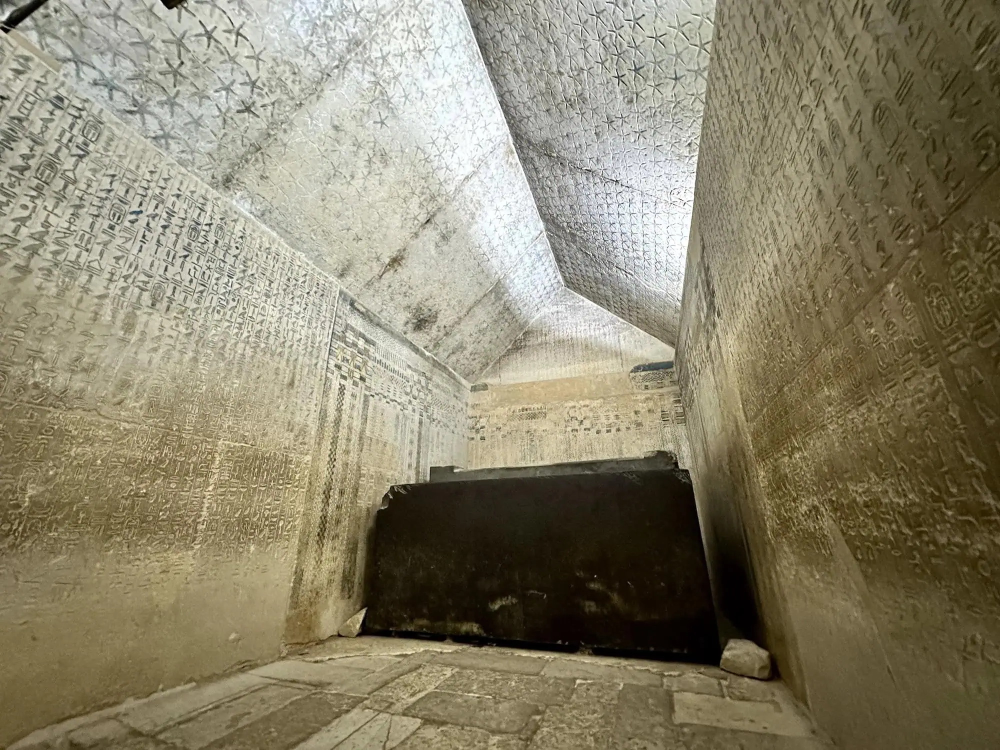 Interior of Pyramid of Unas burial chamber with hieroglyphic pyramid texts covering limestone walls and granite sarcophagus