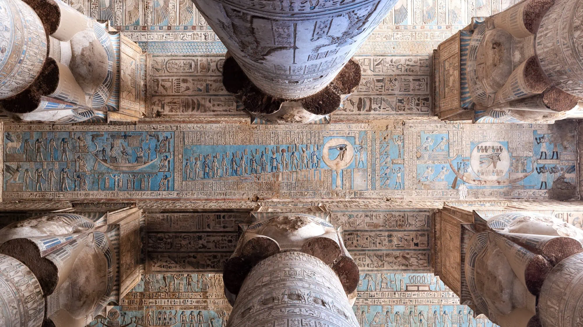 Interior view of Dendera Temple showing elaborate astronomical ceiling decorations with hieroglyphs and colorful blue paintings