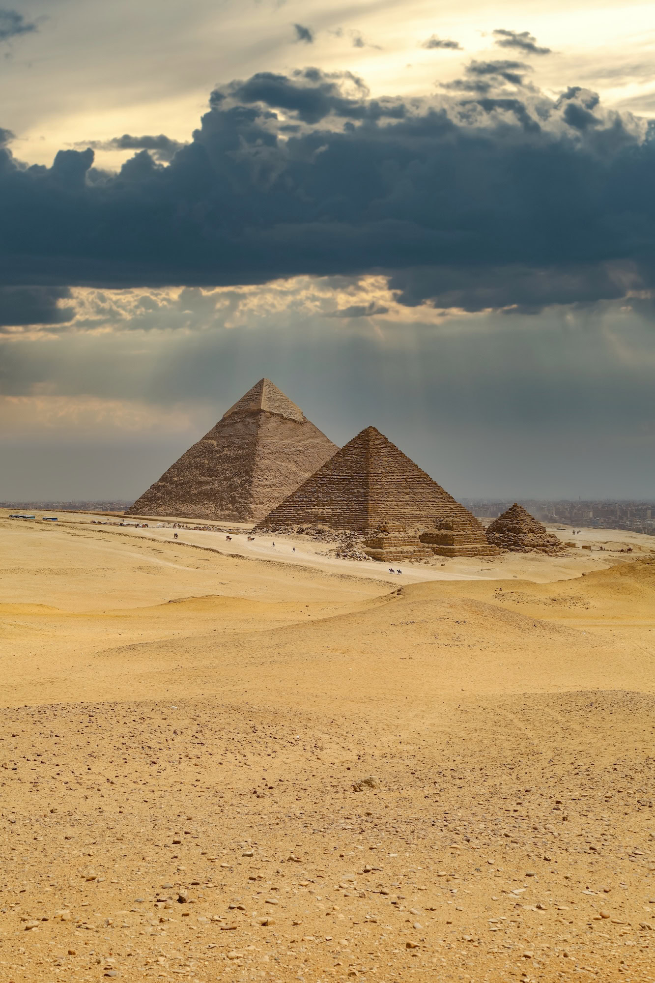 Majestic Pyramids of Giza against clear desert sky with clouds
